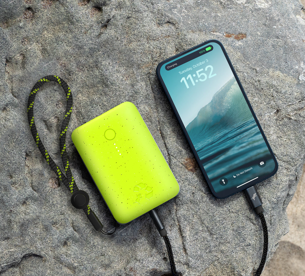 Power bank and phone placed on a rock outdoors.